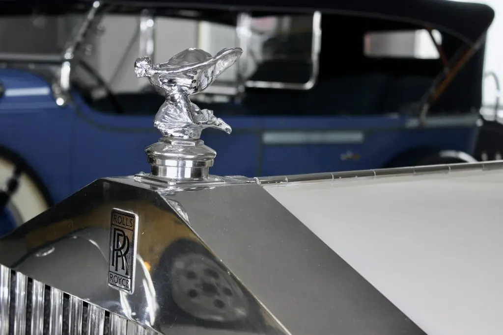 Close up of a kneeling flying lady mascot and black Rolls-Royce logo on an old Rolls-Royce.