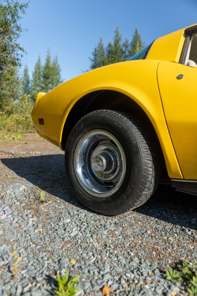 Close up of the back wheel of a 1980 yellow Corvette