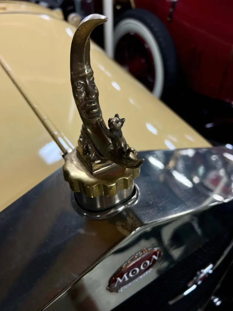 Close up of the Moon Car mascot: A little cat is playing on a crescent moon with a face.