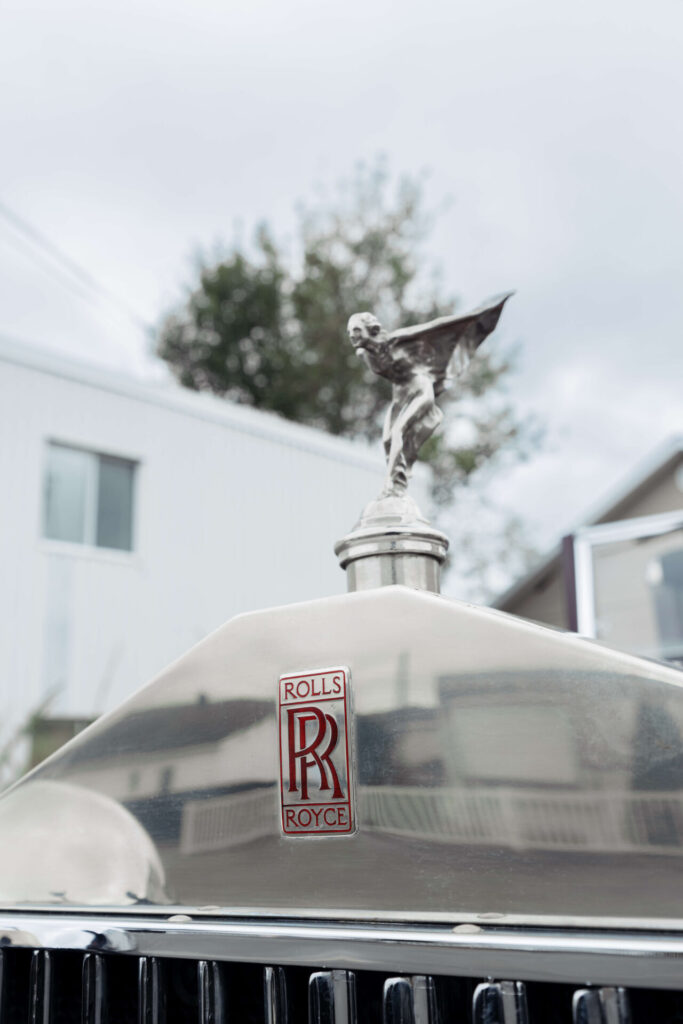 Close up of the Rolls-Royce mascot: the Spirit of Ecstasy or Flying Lady. The Rolls-Royce logo is red.