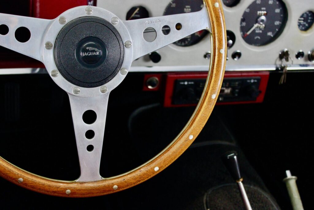 Close up of the steering wheel and dashboard of a Jaguar E-Type, the last car fully imagined by William Lyons