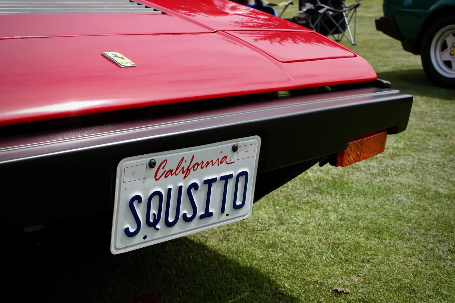 Concorso Italiano: close up of a plate A close up of a vanity plate on a red Ferrari car read "Squisito"