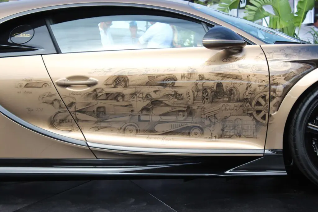 Right side of a Golden Bugatti. Black drawing of classic Bugattis on it.