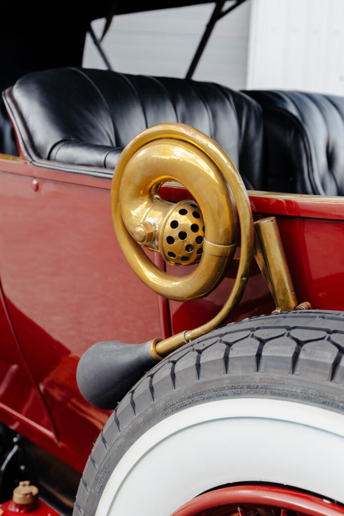 Un gros plan sur le klaxon en bronze d'une voiture de l'Ère du Bronze. Le klaxon est enroulé comme un escargot et semble s'appuyer sur la roue de secours de la voiture.