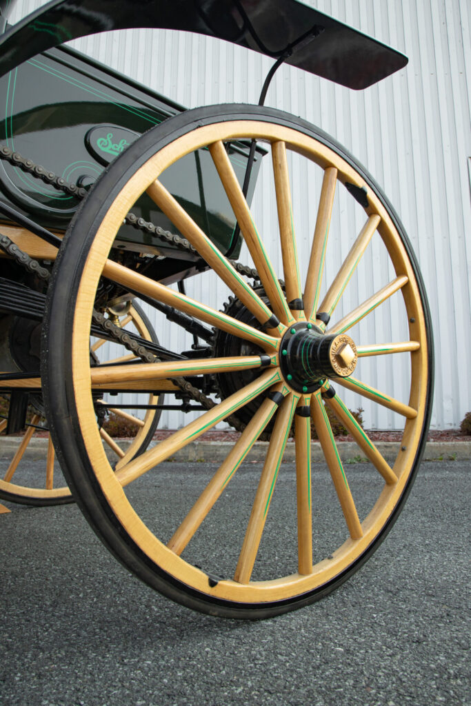 Close up of one of the back wheels. Hard rubber covers the wooden wheels.