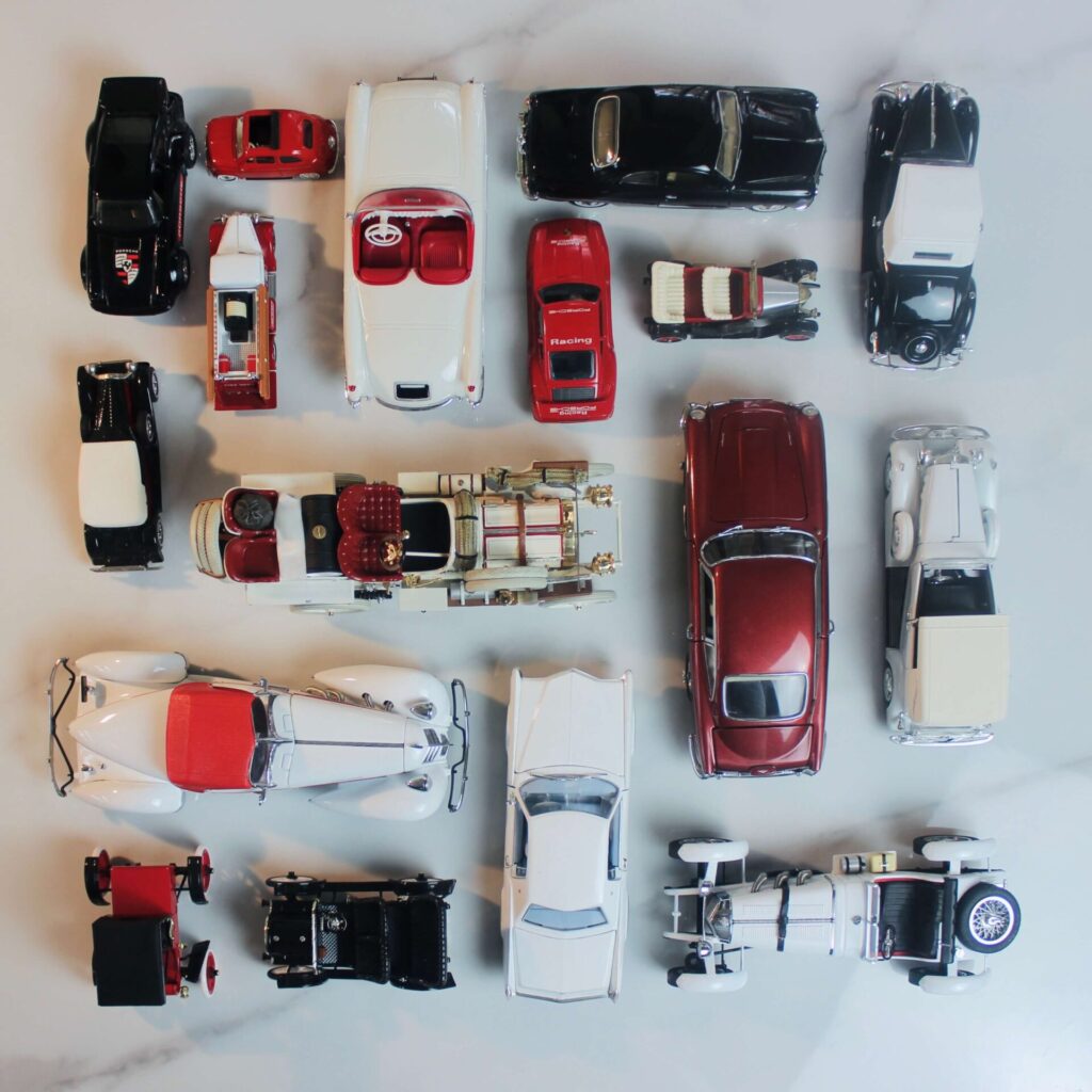 Model cars all in different shades of red white and black lined in a scare in the Knolling technique.