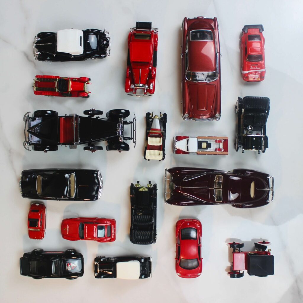 Model cars all in different shades of red, white and black lines in a scare in the Knolling technique.