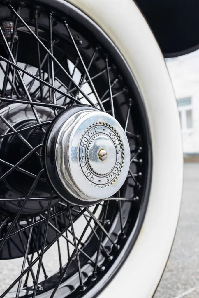 Close up of a white-flanked and metal spoke wheel of a classic Rolls-Royce