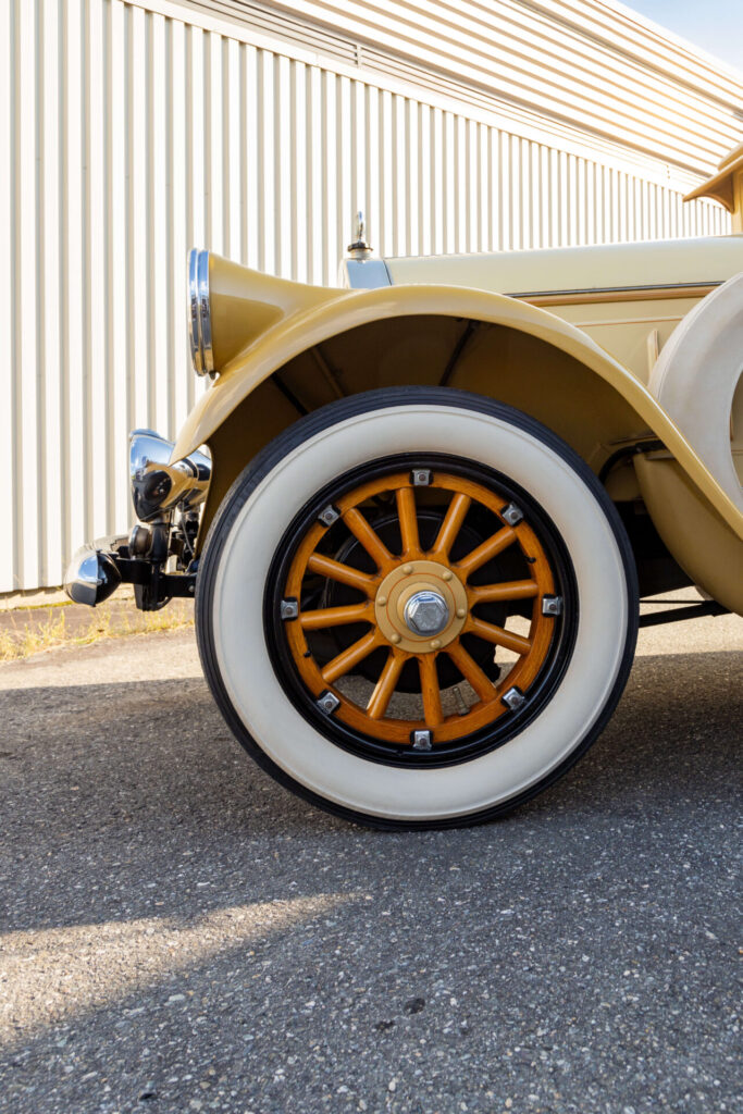 White-flanked tire on a wooden spoke wheel of a yellow Pierce Arrow car