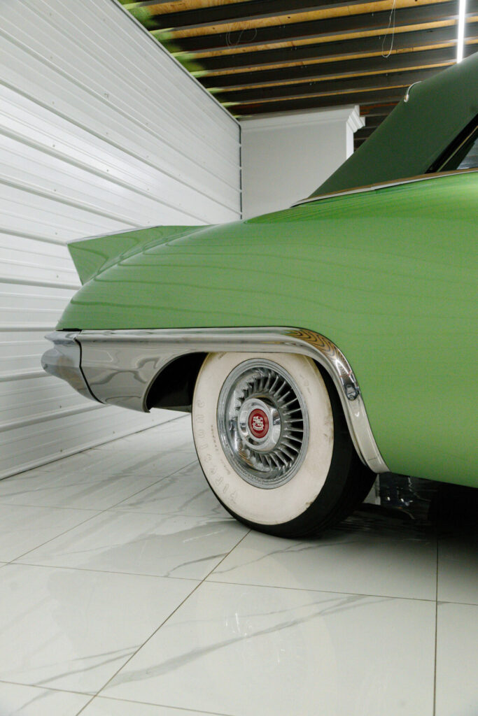 L'arrière d'une Cadillac Eldorado Biarritz verte de 1957. La roue a un pneu à flanc blanc et nous pouvons voir la petite ailette sur l'aile arrière.