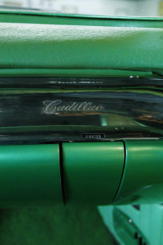 Gros plan sur un badge Cadillac en chrome sur un tableau de bord vert.