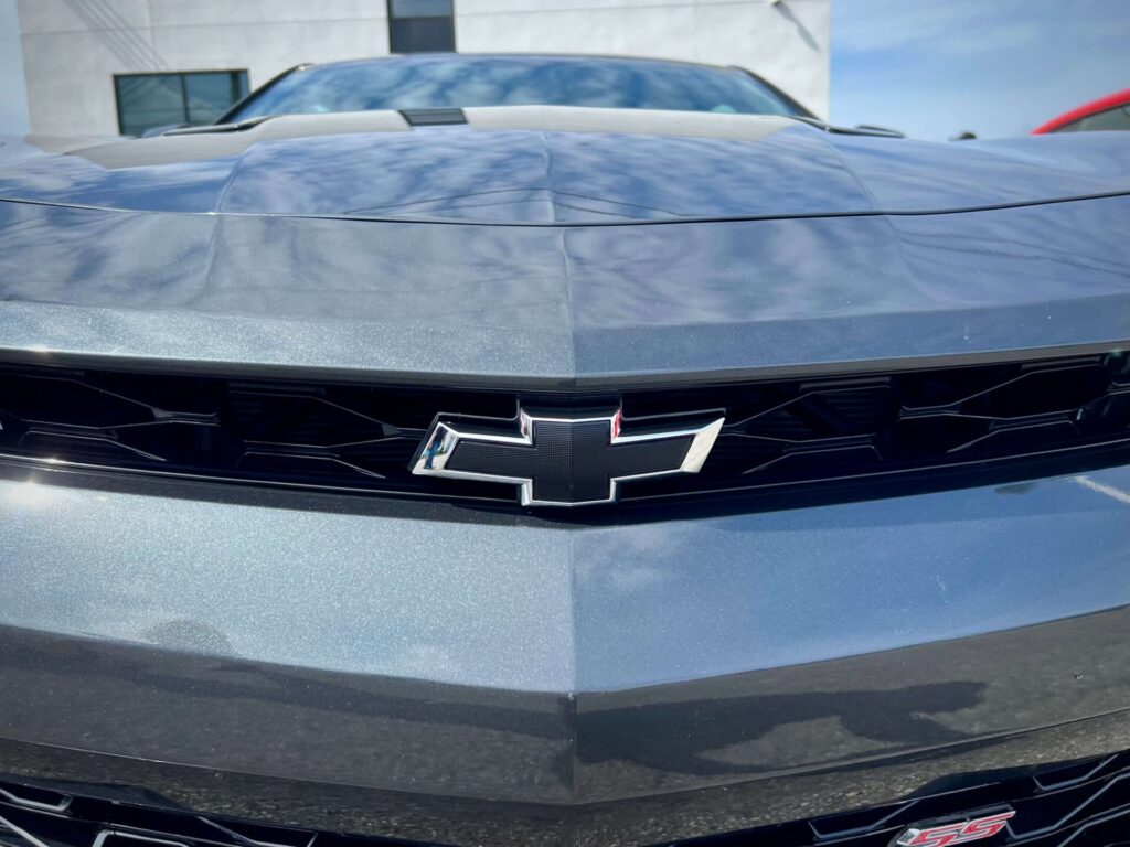 Close up of Chevrolet's bow-tie logo on a grey car.