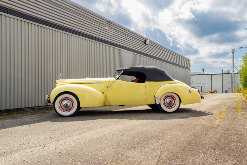 Vue de profil d'une Packard-Darrin Victoria jaune avec un toit noir.