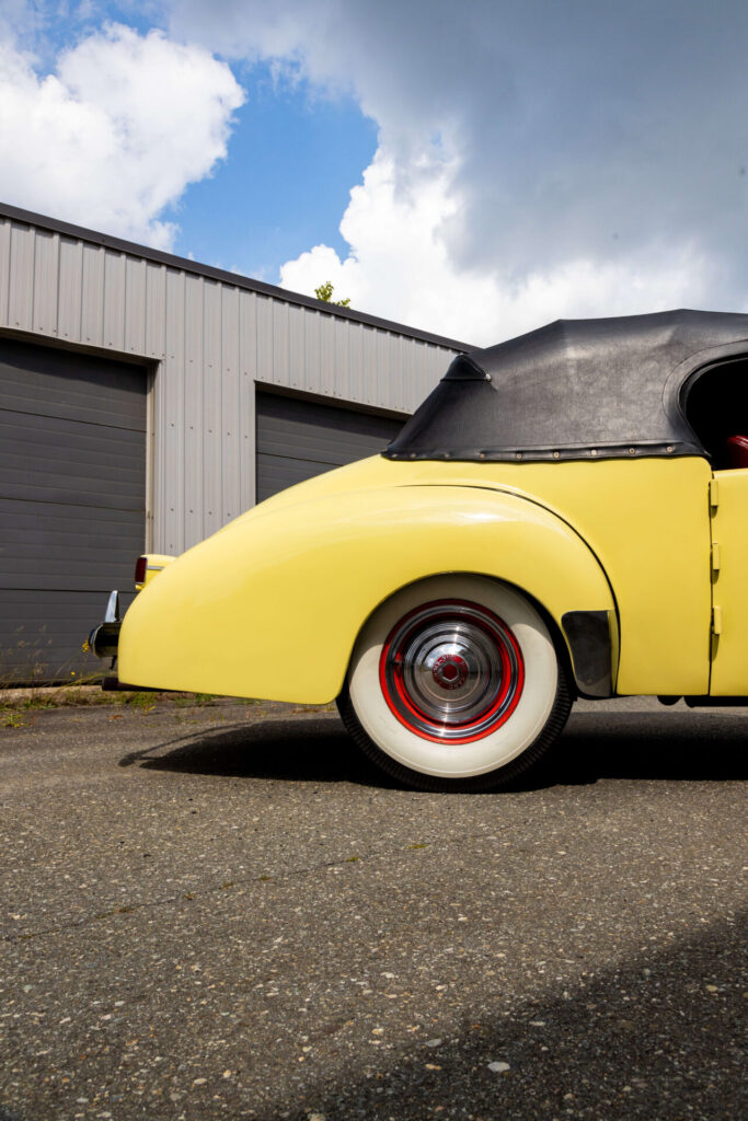 Gros plan sur le profil arrière de la Packard-Darrin de 1940. Un pneu à flanc blanc est visible.