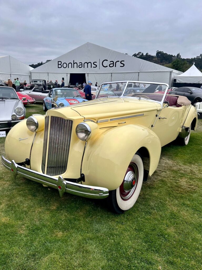 Voiture Packard-Darrin jaune photographiée sur la pelouse devant une tente blanche Bonhams Cars.