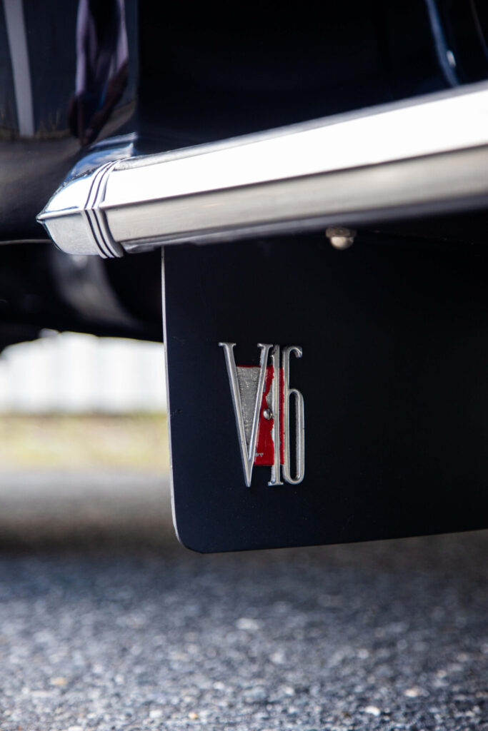 "V16" on a red circle is the metal badge seen on a panel close to the floor. The Cadillac V16 was a halo car and its impressive engine was clearly advertised on the car through badging.