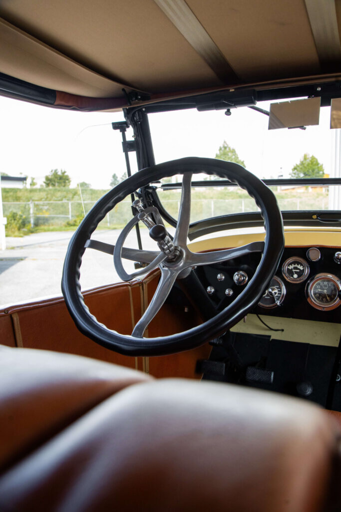 Close up view of a black steering wheel viewed from the back seat.