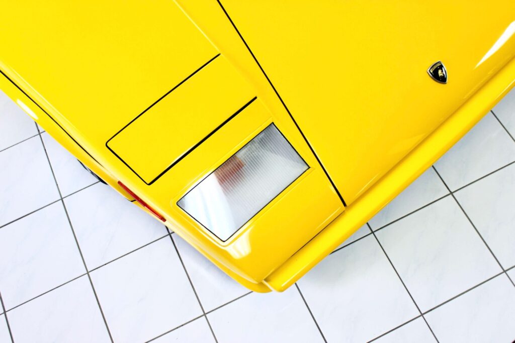 
Vue de dessus du phare escamotable sur une Countach jaune. La photo encadre la voiture en forme de coin, rappelant le style distinctif de la voiture.