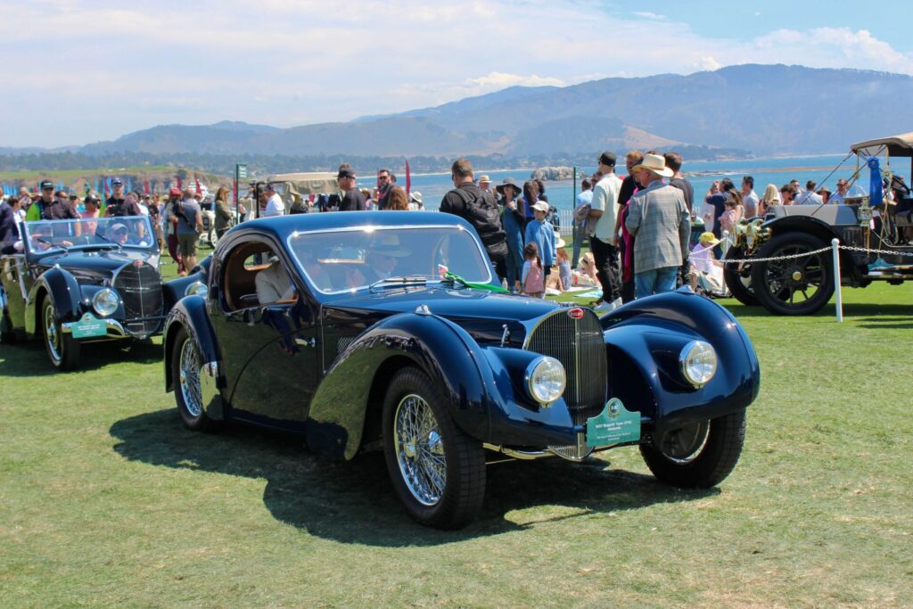 Bugatti noire des années 1930 conduite devant une foule sur l'herbe verte au Concours d'élégance de Pebble Beach