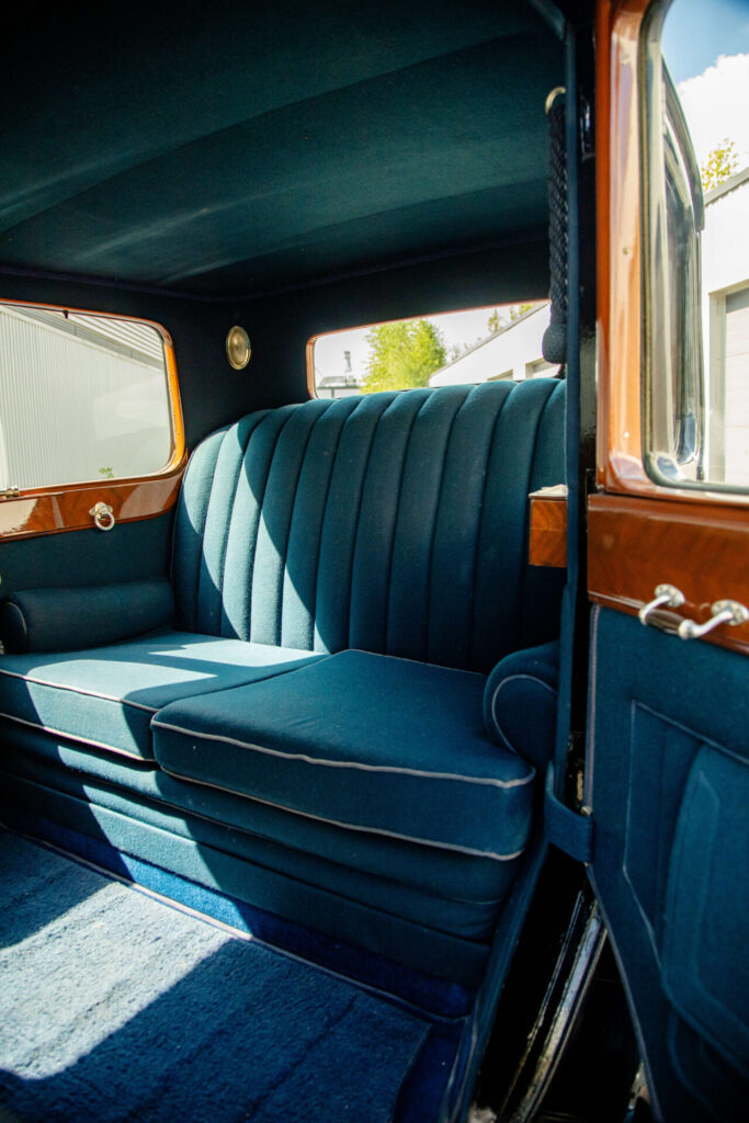 Backseat of a town car. The seat, door panels and the floor are covert in a blue velvety fabric.