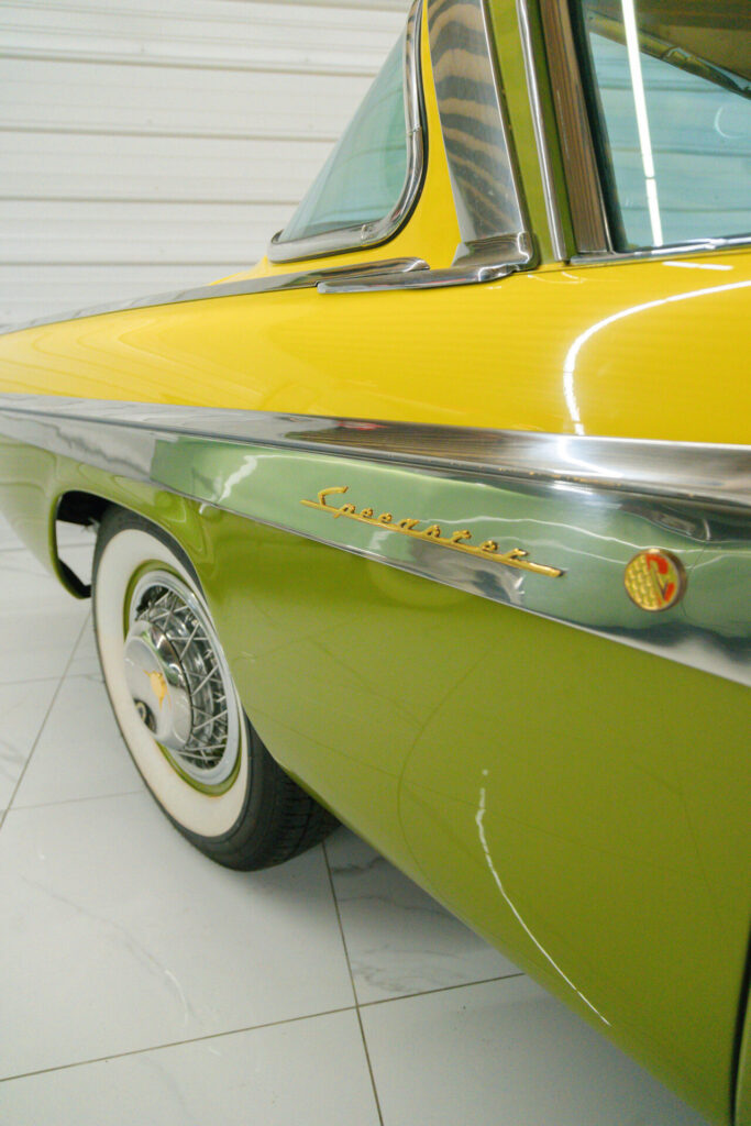 Vue rapprochée d'une plaque de modèle 'Speedster' plaquée or sur une Studebaker President Speedster jaune et verte de 1955.