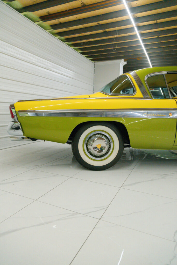 Vue rapprochée de l'arrière d'une voiture jaune et verte des années 1950. Une ligne chromée séparait les deux couleurs au milieu de la voiture.