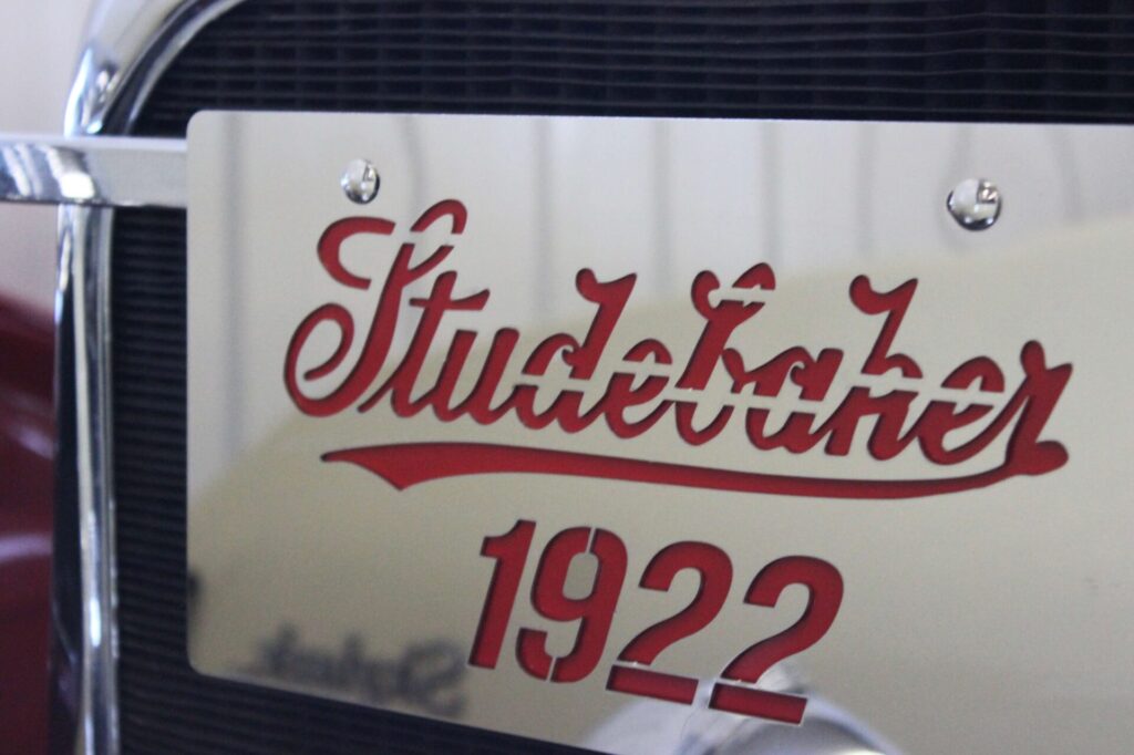 Une plaque chromée avec une découpe rouge inscrite "Studebaker 1922."