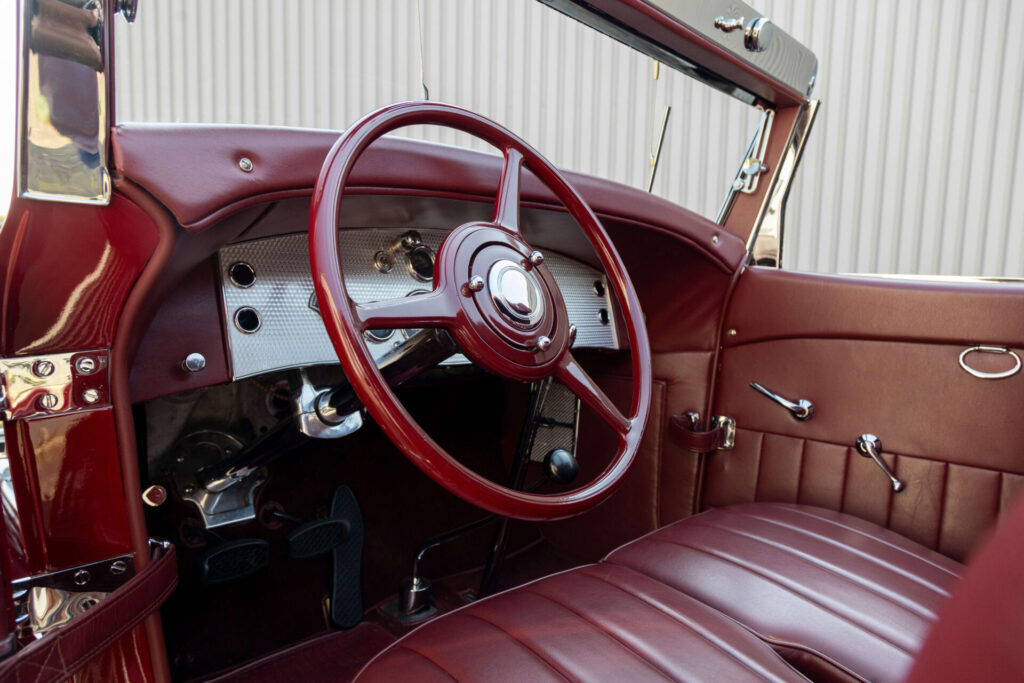 L'intérieur d'une voiture classique. Les sièges en cuir rouge sont de la même couleur que l'arrière du tableau de bord et le volant.