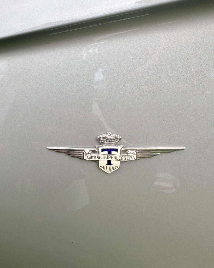 A Touring badge on a grey car. the badge is a T on a shied with spread out wings on each side.