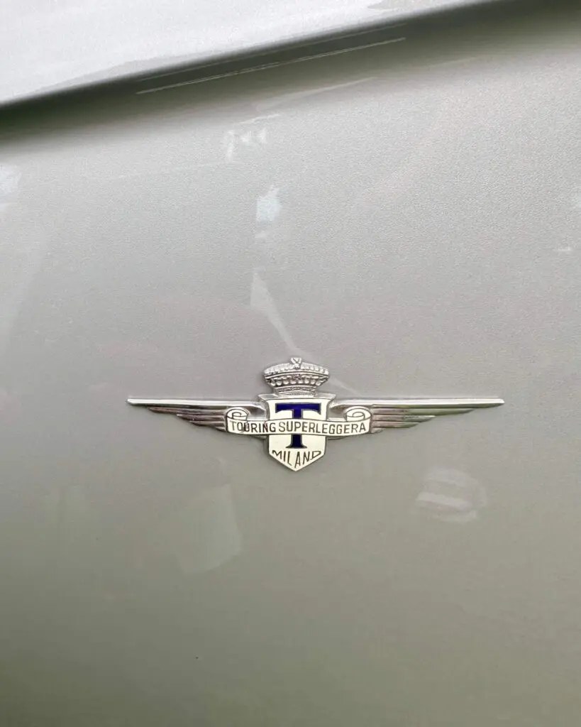A Touring badge on a grey car. the badge is a T on a shied with spread out wings on each side.