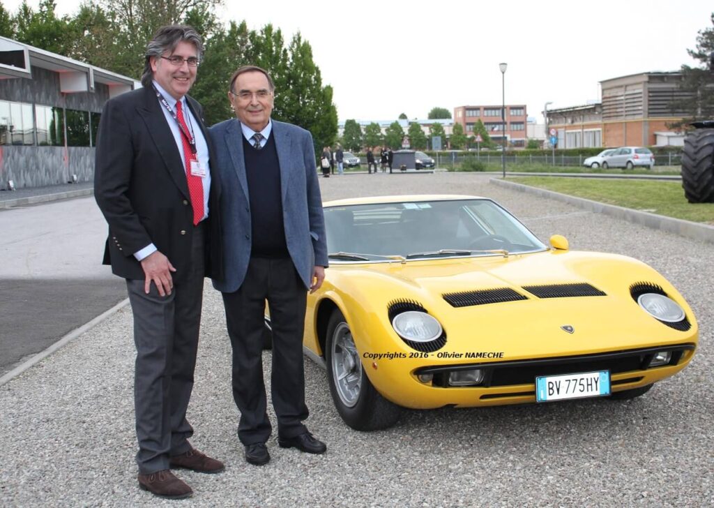 Deux hommes en habit pause à côté d'une voiture sport jaune