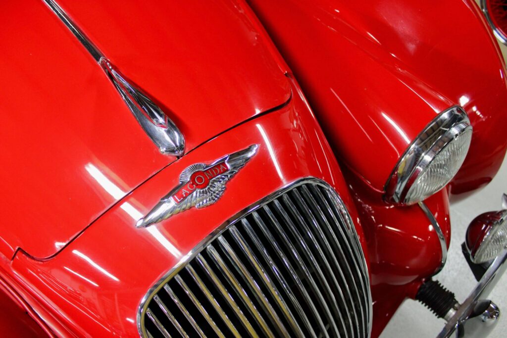 Close up and bird's-eye-view of the front of a red car with prominent grille and headlights.